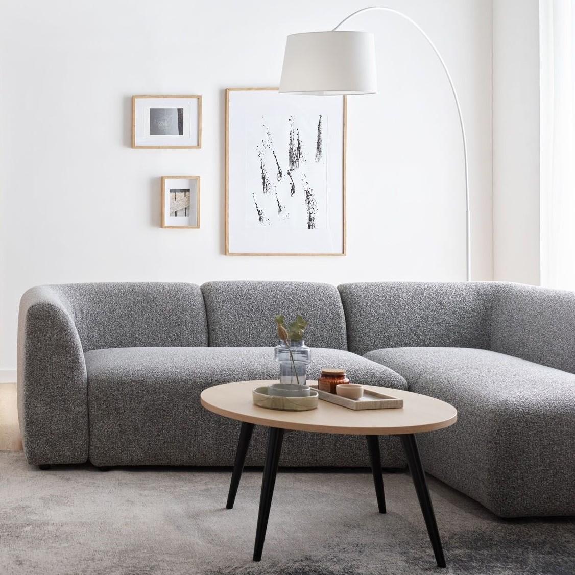 Minimalistyczny salon z szarą sofą i białymi ścianami.