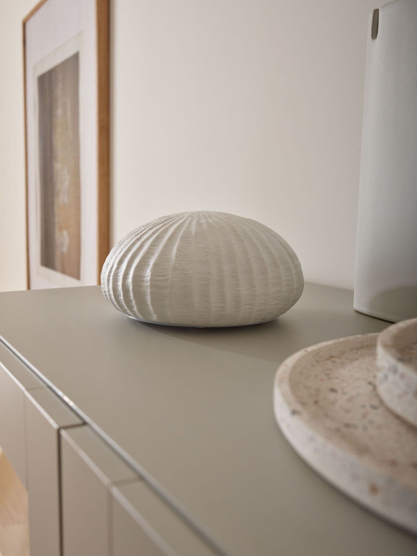 Biała dekoracja ceramiczna na beżowej komodzie.