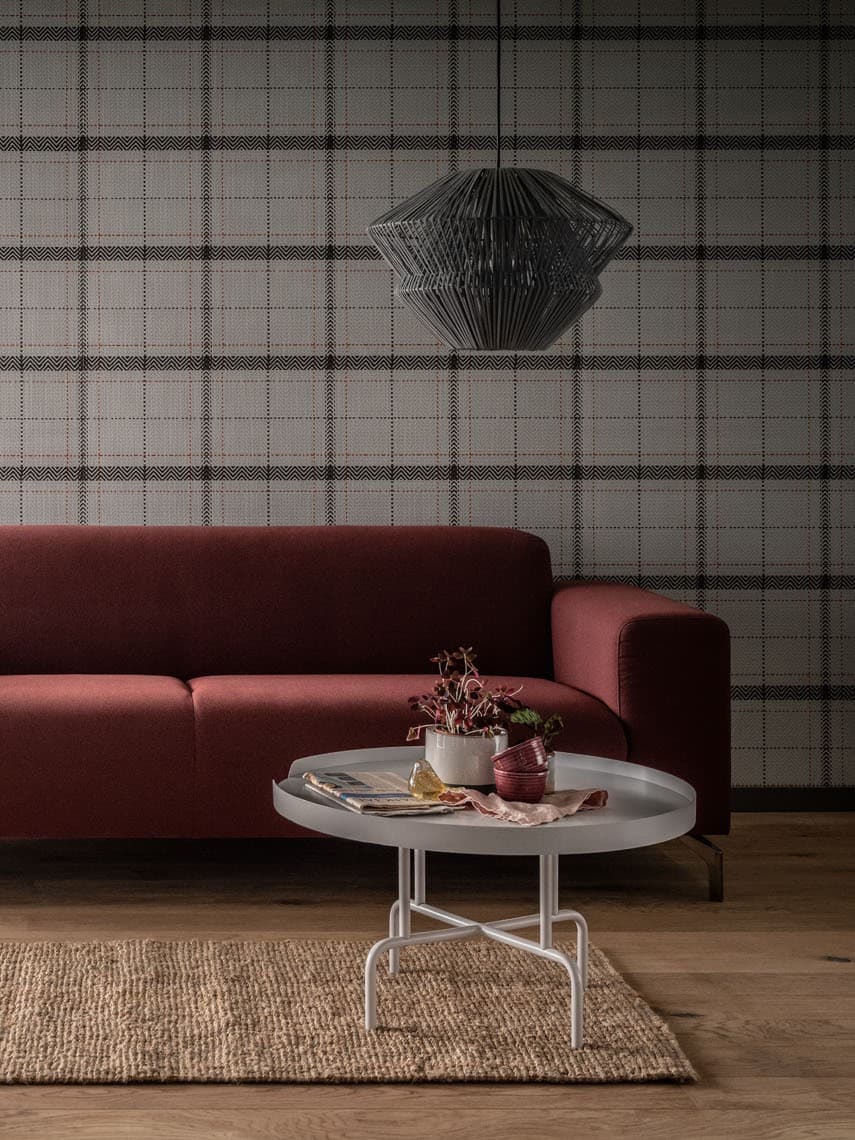 Czerwony narożnik w salonie z geometryczną tapetą.