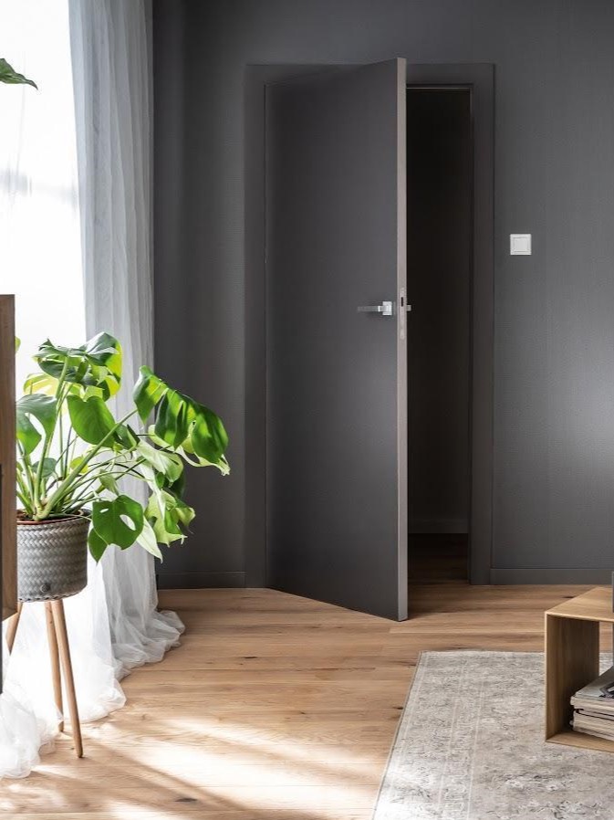 Nowoczesny wiatrołap z czarnymi drzwiami i drewnianą podłogą