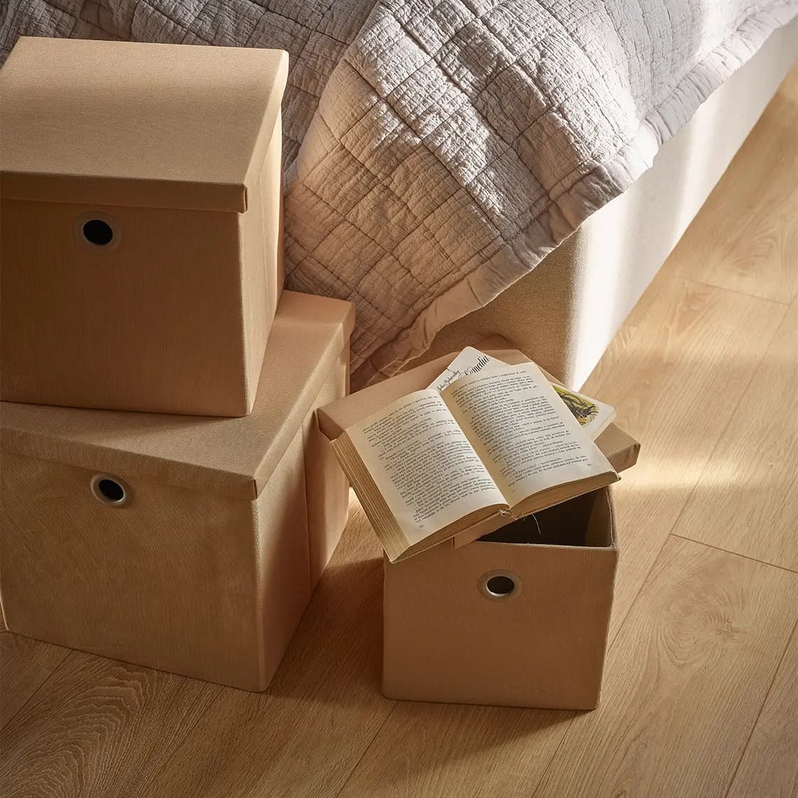 Kartonowe pudełka z książkami obok łóżka.