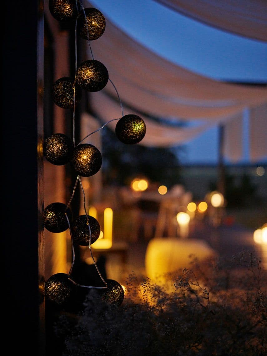 Girlandy świetlne tworzące ciepły i klimatyczny nastrój na tarasie po zmroku.